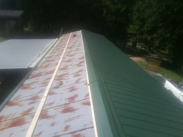 Old rusted panels beside newly installed green metal roofing — Wind Damage Roof Repair by Roofing Brothers in Bickleton